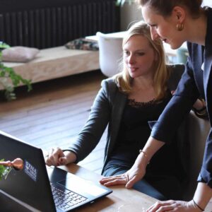 two women working over a laptop